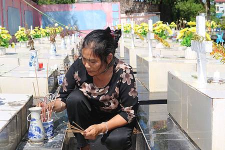 Nguyen Thi Nhiem zündet Räucherstäbchen auf einem Friedhof an und betet für die Seelen der ungeborenen Kinder.