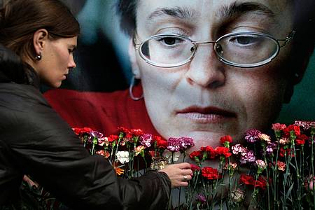 Eine Frau legt in Moskau Blumen vor einem Porträt der ermordeten russischen Journalistin Anna Politkowskaja nieder.