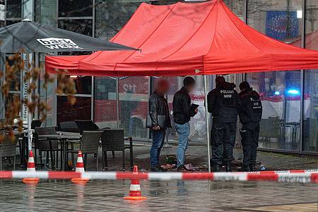 Polizeibeamte untersuchen unter einem Zeltdach den Tatort in Gummersbach.