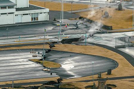 Aus Rissen im Boden in der isländsichen Stadt Grindavik steigt Rauch auf (Luftaufnahme mit Drohne).