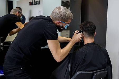 Ein Friseur schneidet die Haare eines Kunden in einem Friseursalon.